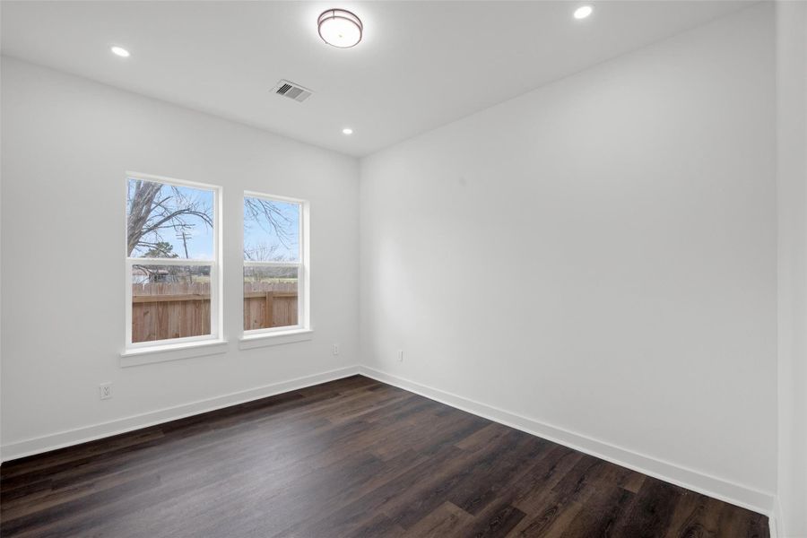 Luminous room with modern recessed lighting, large windows, and dark hardwood floors, offering a clean, open space perfect for customization.