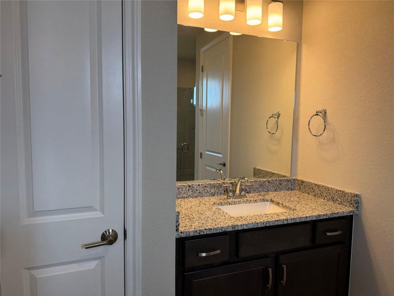 A well-appointed bathroom features a single vanity with stone counters and a spacious mirror.