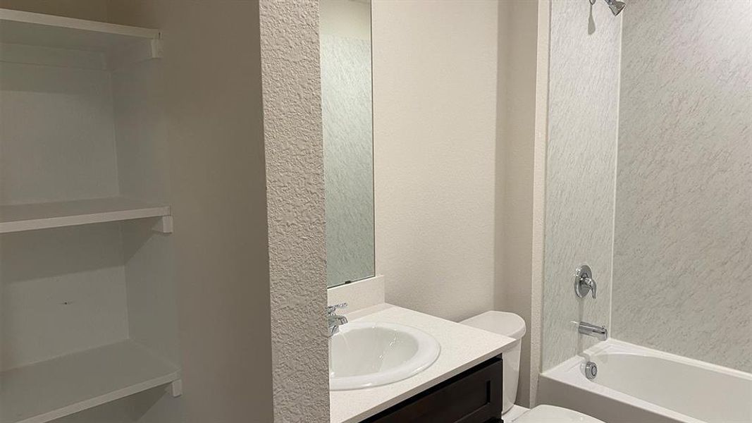 Bathroom featuring a textured wall, vanity, and shower / tub combination