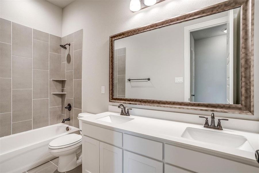 Full bathroom with tiled shower / bath, vanity, toilet, and tile patterned floors