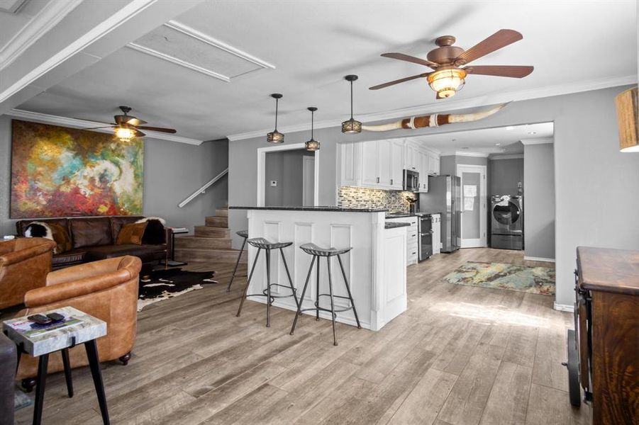 Kitchen featuring light hardwood / wood-style flooring, tasteful backsplash, a kitchen breakfast bar, white cabinets, and separate washer and dryer