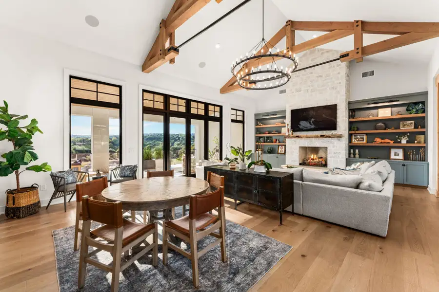 Dining space featuring a fireplace, high vaulted ceiling, a chandelier, light wood finished floors, and beam ceiling Dining space featuring a fireplace, high vaulted ceiling, a chandelier, light wood finished floors, and beam ceiling