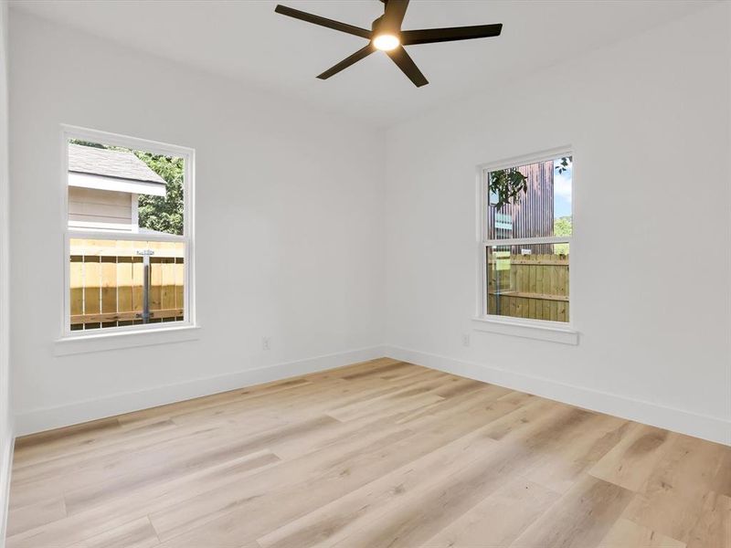 Empty room with ceiling fan and light wood-type flooring