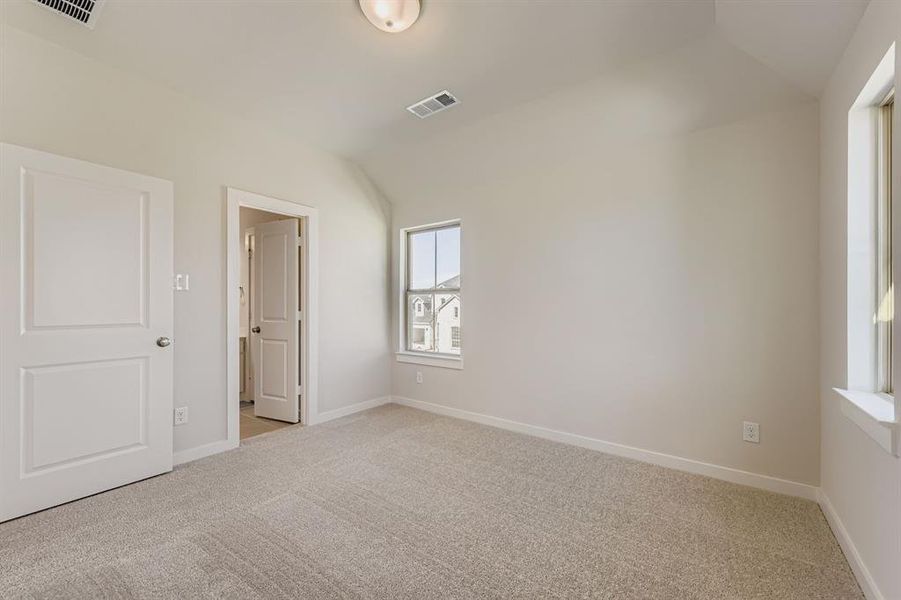 Unfurnished bedroom featuring light carpet and lofted ceiling