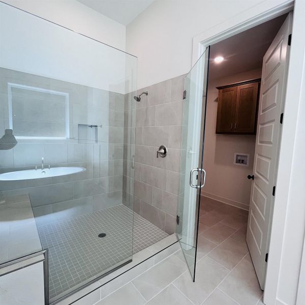 Glass-enclosed shower with a tiled bench, rain showerhead, and handheld spray