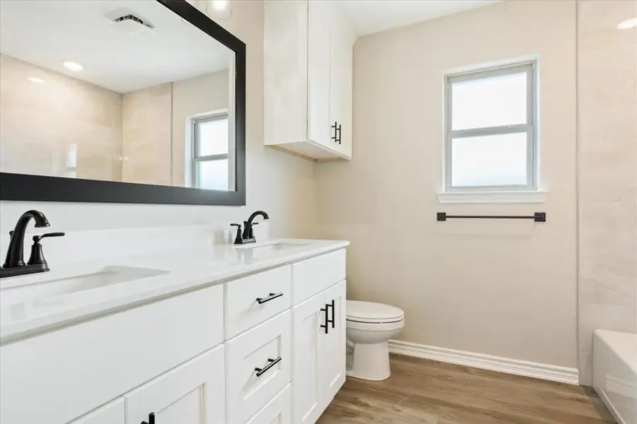 Full bathroom featuring double vanity and wood finished floors Full bathroom featuring double vanity and wood finished floors