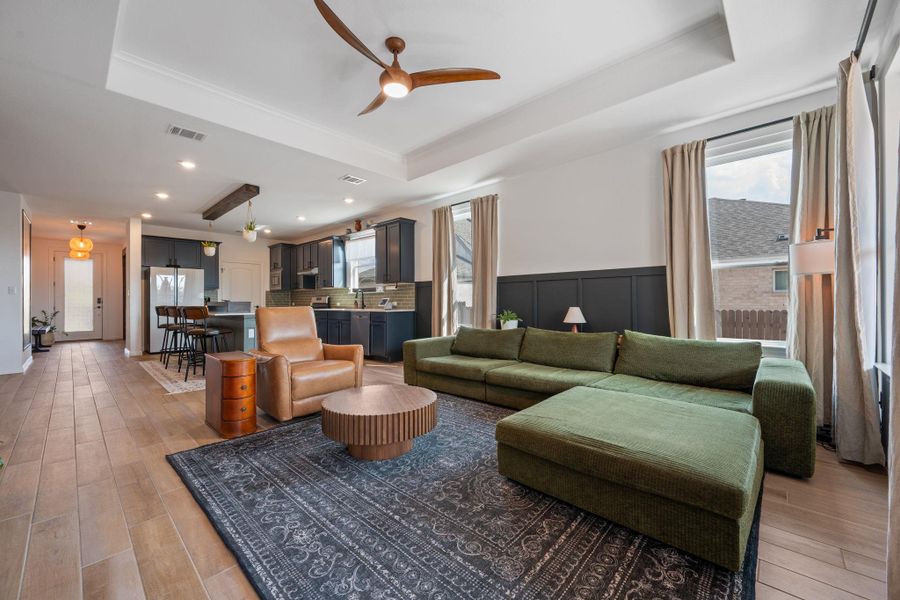 Living room with a tray ceiling, a ceiling fan, light wood-type flooring, and recessed lighting Living room with a tray ceiling, a ceiling fan, light wood-type flooring, and recessed lighting