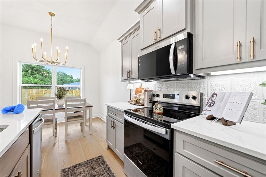 Kitchen featuring light wood-finish flooring, white countertops, and light gray cabinetry with gold-toned hardware