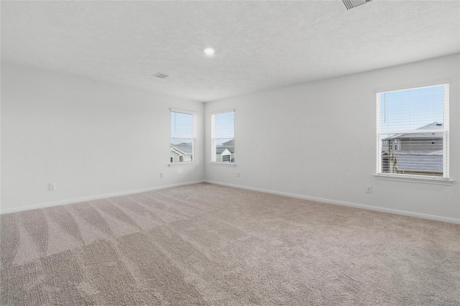 Relax and recharge in this stunning primary suite! Enjoy the comfort of plush carpeting, neutral-toned walls, high ceilings, recessed lighting, and large windows that fill the room with natural light.