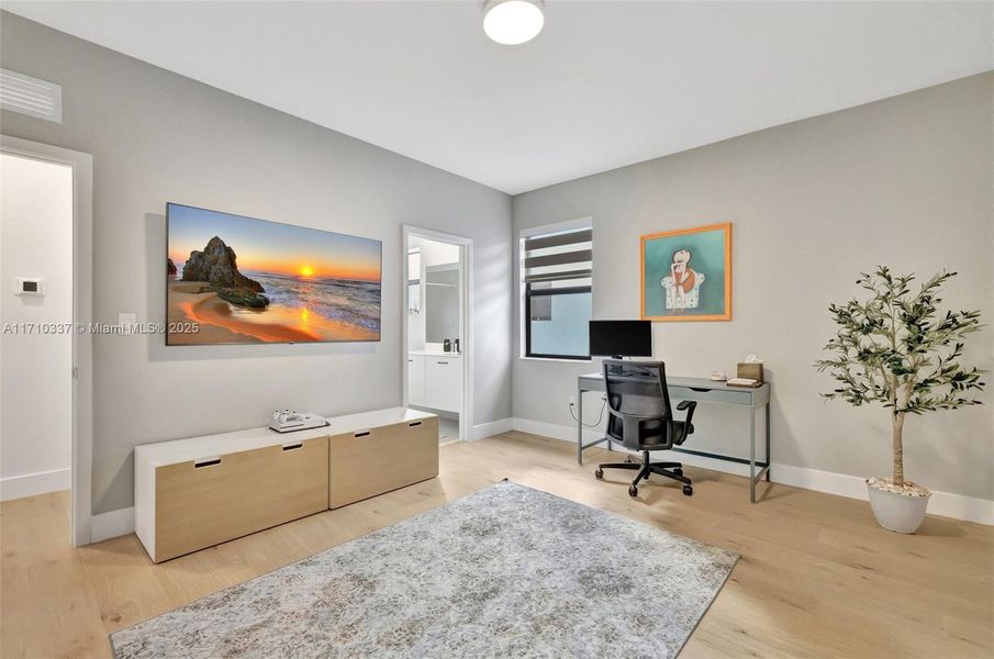 Large neutral painted guest bedroom upstairs at end of hallway, overlooks side of home