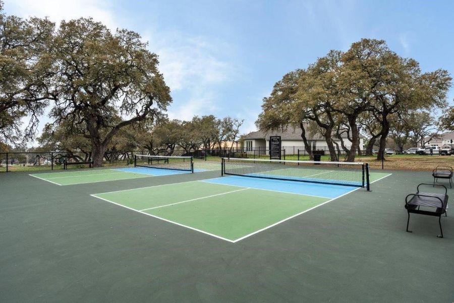 Two outdoor courts featuring green and blue playing surfaces, white court lines, and black nets
