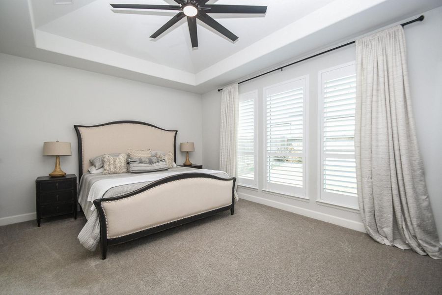 Primary bedroom has coffered ceiling, oversized ceiling fan, and Plantation Shutters