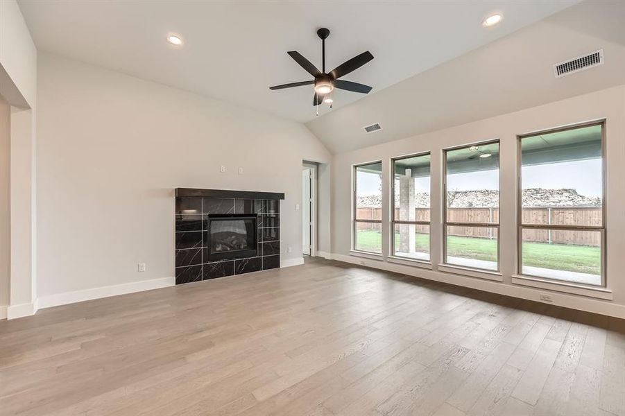 Unfurnished living room with baseboards, lofted ceiling, ceiling fan, and visible vents Unfurnished living room with baseboards, lofted ceiling, ceiling fan, and visible vents