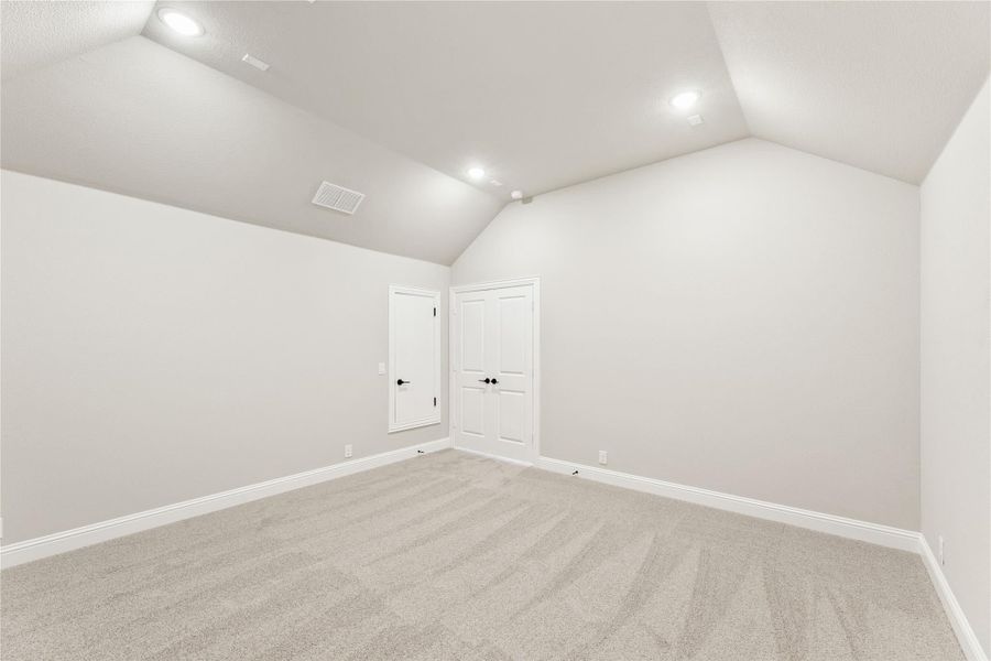 Empty bedroom with vaulted ceiling, gray carpet, and two white doors Empty bedroom with vaulted ceiling, gray carpet, and two white doors