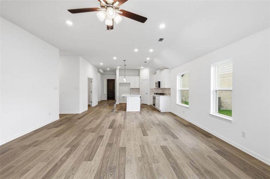 Expansive open-concept living area featuring wood-finish flooring, recessed lighting, and a ceiling fan