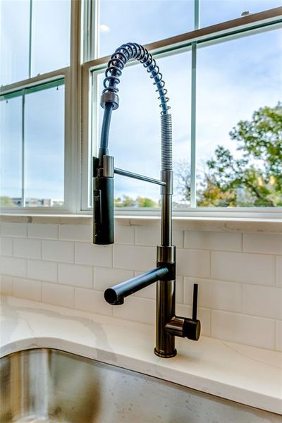 Details with decorative backsplash, light stone counters, and sink