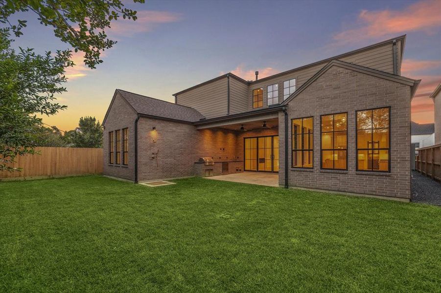 The home’s rear exterior mirrors the modern design of the front, with large windows and a cozy covered patio, seamlessly connecting indoor and outdoor living spaces.