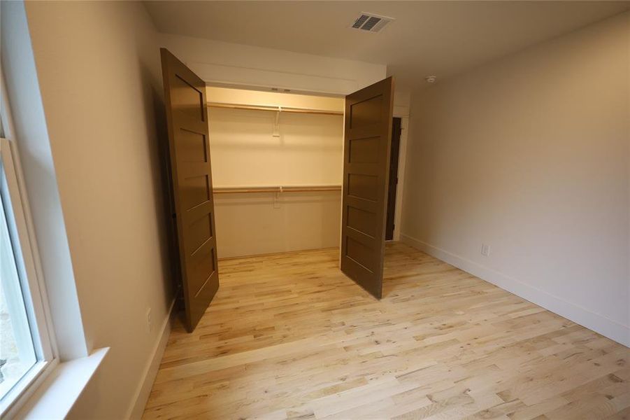 Unfurnished bedroom featuring light wood flooring and a closet