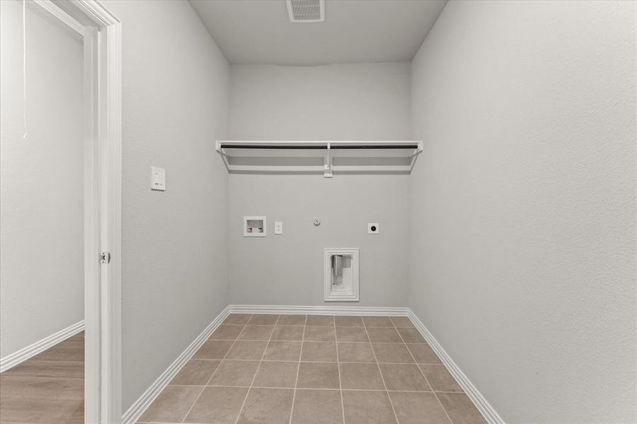 Clothes washing area featuring gas dryer hookup, hookup for an electric dryer, light tile patterned floors, and hookup for a washing machine