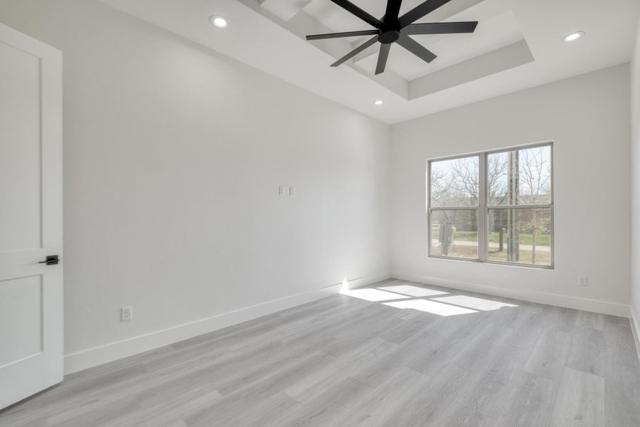 Spare room featuring recessed lighting, light wood-style flooring, baseboards, and a tray ceiling