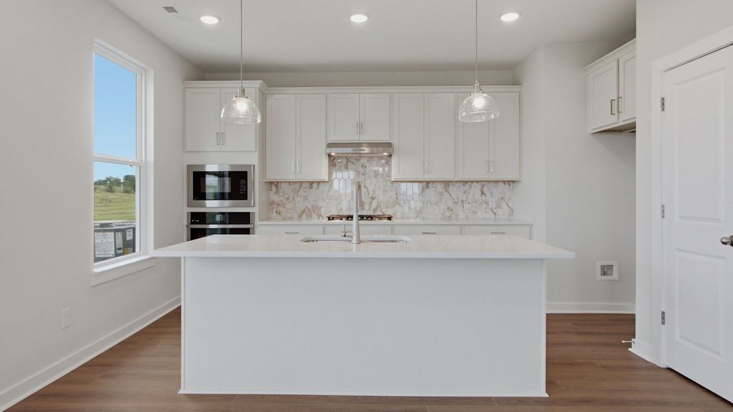 Kitchen with island, white cabinets, tile backsplash, and gas cooktop