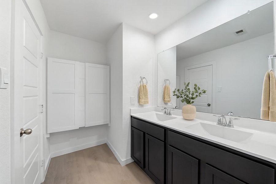 Modern bath with dual vanities, large framed mirror, and dark cabinetry. Features a combination shower/tub with tile surround and built-in shelving.