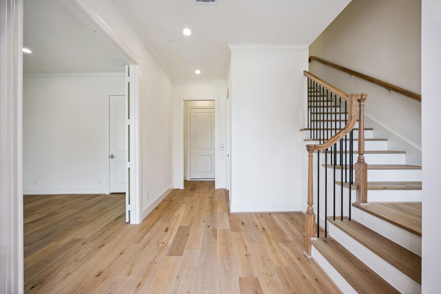 Light-filled entry with hardwood floors and staircase leading to the main living level.