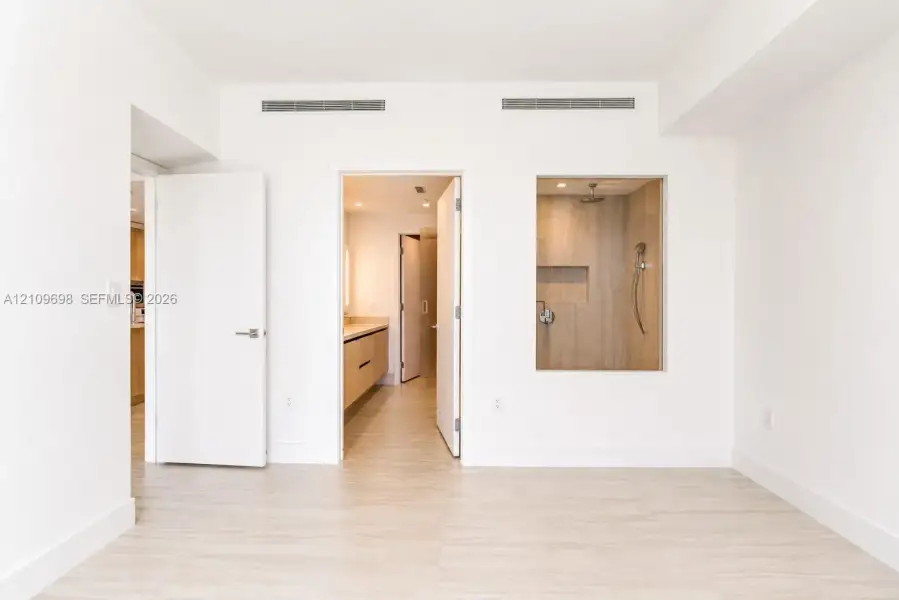 Interior space featuring wood-finish flooring, a recessed shower enclosure with wood-finish wall tile, a built-in recessed shower niche, and a wall-mounted shower fixture