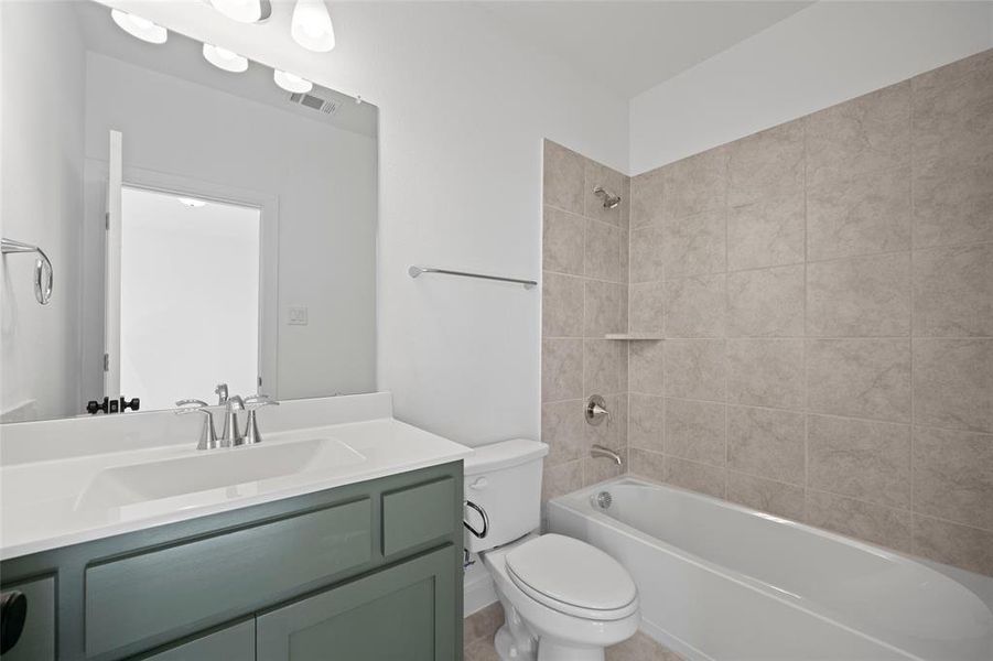 Full bathroom featuring vanity, tiled shower / bath combo, and toilet