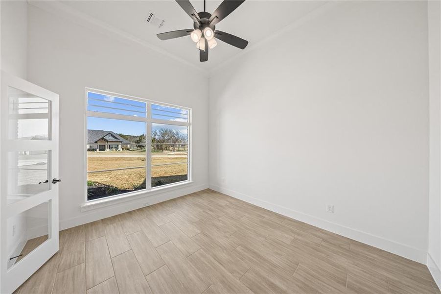 Spare room with wood finish floors, crown molding, and ceiling fan