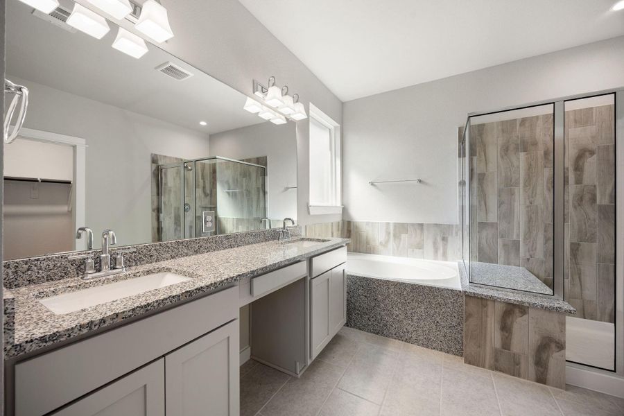 Primary bath with his/her sinks, vanity area, soaking tub and standup shower.