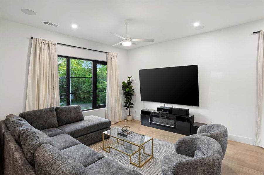 Bright living space featuring light wood-finish flooring and a ceiling fan
