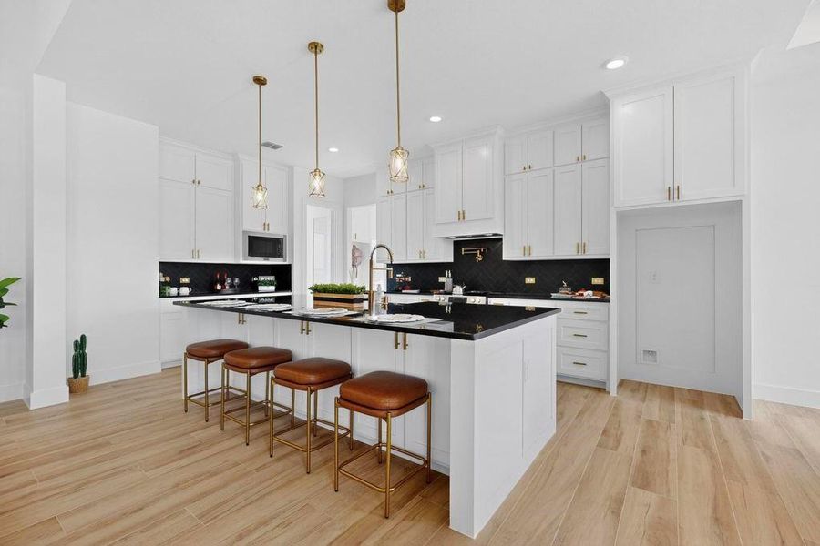 Kitchen featuring a large island, white cabinets, a breakfast bar area, hanging light fixtures, and recessed lighting