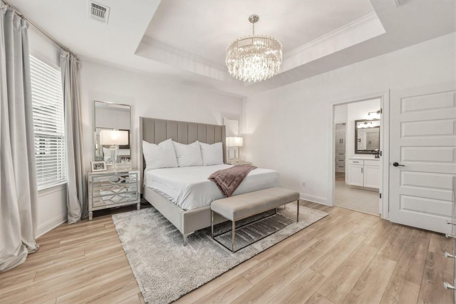Spacious bedroom featuring a tray ceiling, and a prominent chandelier