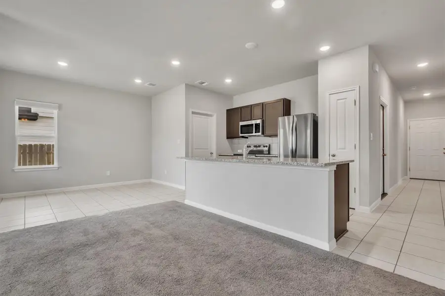 An open-concept living space integrates a well-appointed kitchen with an inviting tiled and carpeted area.