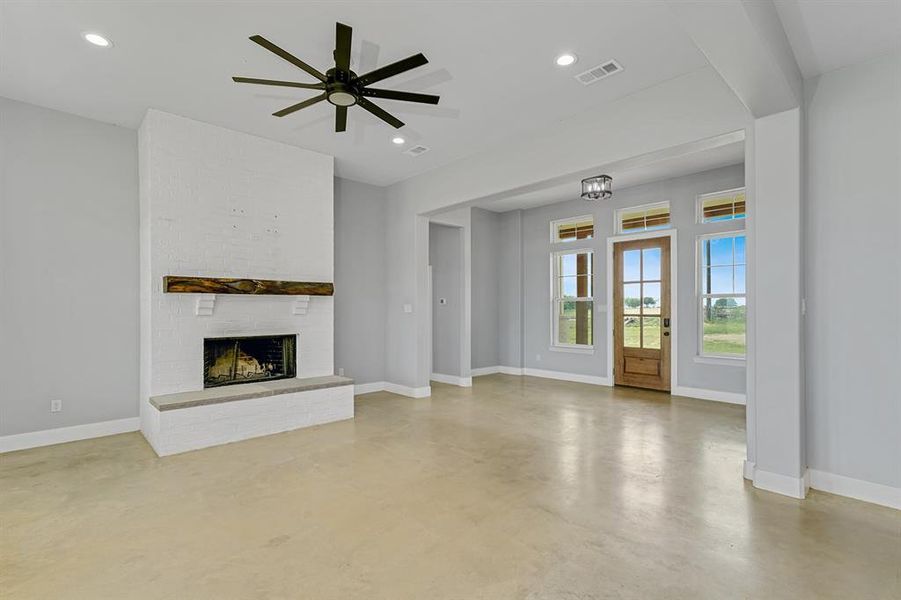 Unfurnished living room featuring finished concrete floors, baseboards, a brick fireplace, ceiling fan, and recessed lighting
