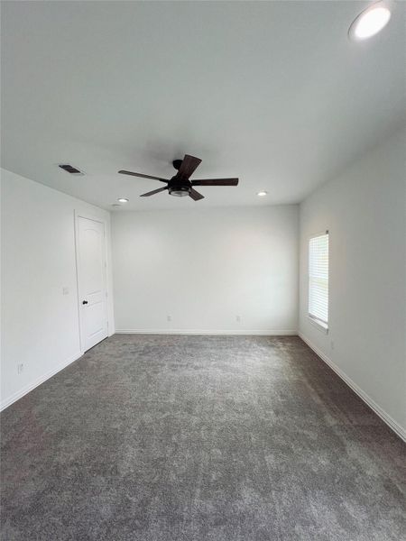 Empty room featuring recessed lighting, dark carpet, visible vents, baseboards, and ceiling fan Empty room featuring recessed lighting, dark carpet, visible vents, baseboards, and ceiling fan