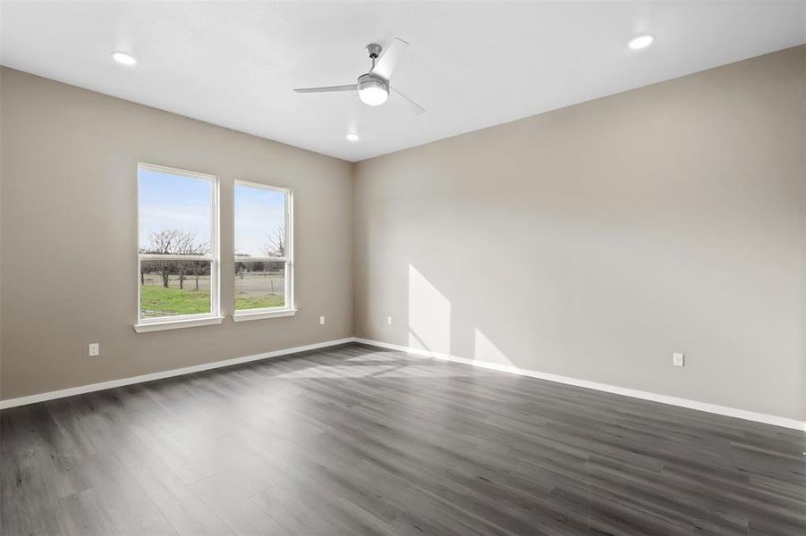 Empty room featuring ceiling fan and dark hardwood / wood-style flooring