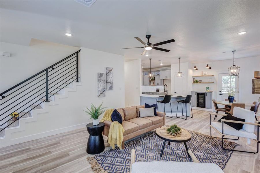 Living room featuring ceiling fan with notable chandelier, beverage cooler, sink, and light hardwood / wood-style flooring