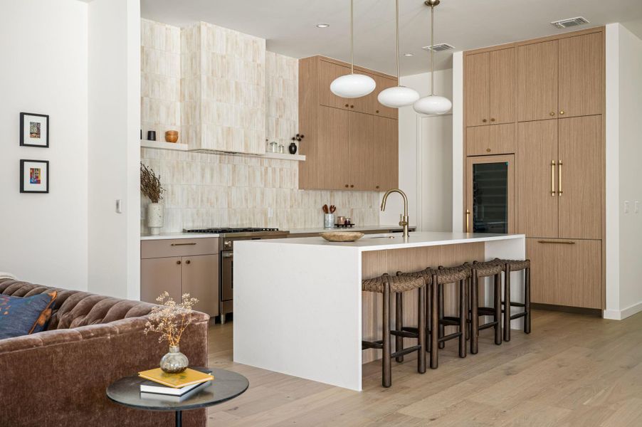 Rich wood cabinetry and a waterfall island anchor this sophisticated, open culinary space.