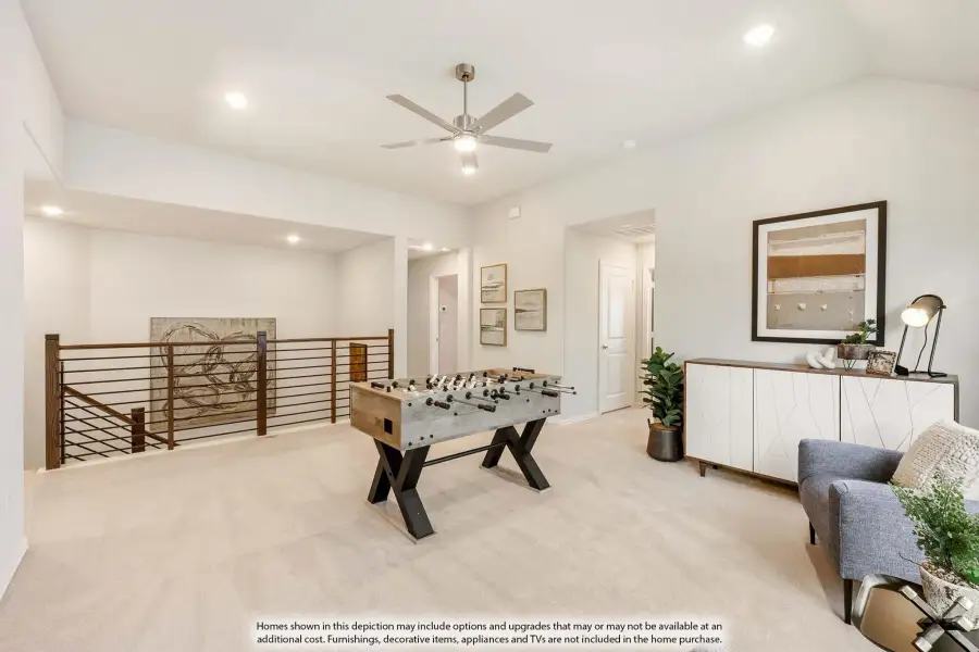 Upstairs game room with foosball table, ceiling fan, carpet flooring, and open railing overlooking lower level