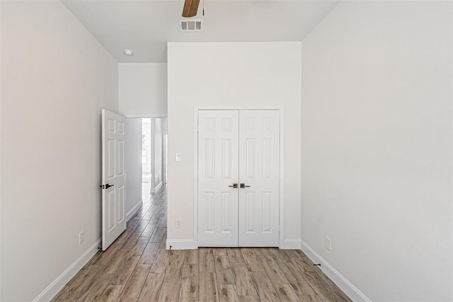 Unfurnished bedroom with wood finished floors, a closet, and a ceiling fan