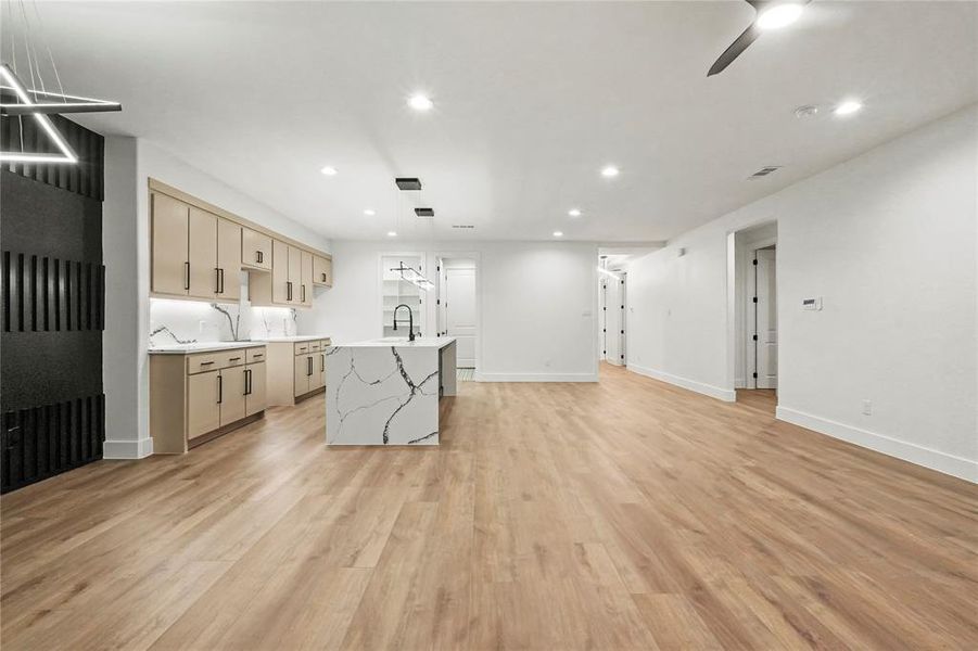 Kitchen with light stone counters, recessed lighting, a center island with sink, light wood-type flooring, and open floor plan Kitchen with light stone counters, recessed lighting, a center island with sink, light wood-type flooring, and open floor plan