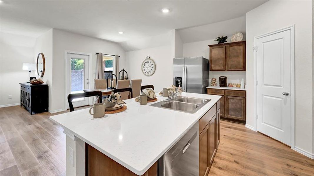 Kitchen featuring a center island with sink, stainless steel appliances, light wood-type flooring, recessed lighting, and vaulted ceiling