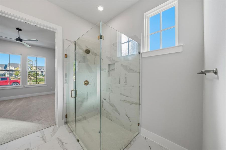 Full bathroom featuring marble look tiles, healthy amount of natural light, a marble finish shower, a ceiling fan, and recessed lighting