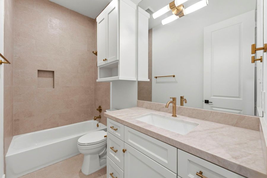 Bathroom #4 (Attached to Bedroom #3) Featuring a shower/ tub combo, WHITE cabinets, gold hardware, MODERN light fixture, and SPA- like inspired tile.