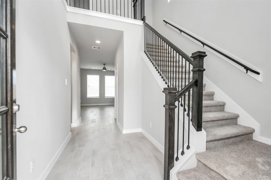 The majestic entryway allures with its high ceilings, embellished with sophisticated wood-look tile flooring and sleek oversized baseboards.