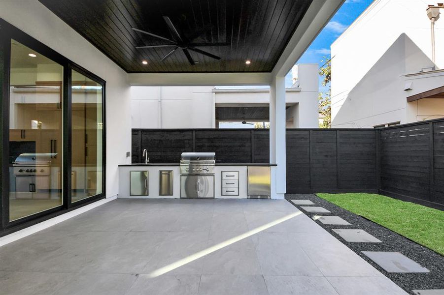 Enjoy outdoor living at its finest with this covered patio, complete with a built-in stainless steel kitchen, including a grill and sink.