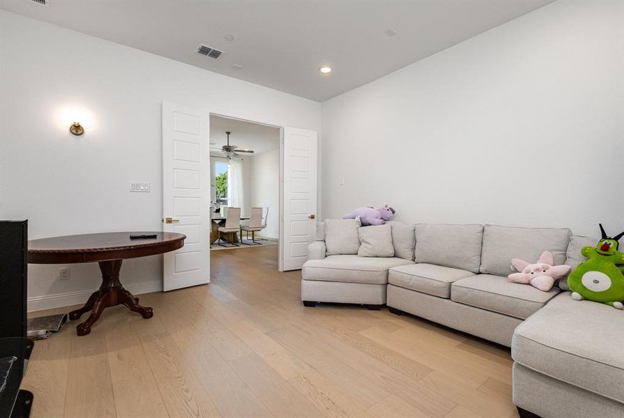Living area with light wood-style flooring and recessed lighting