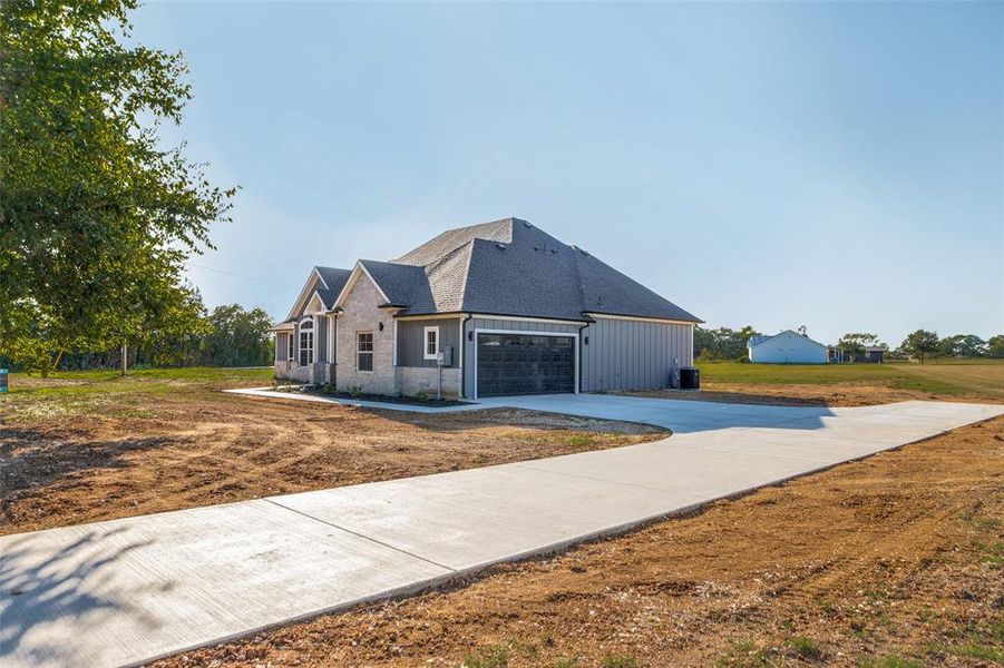 View of front of property with driveway, a garage, stone siding, a shingled roof, and board and batten siding View of front of property with driveway, a garage, stone siding, a shingled roof, and board and batten siding